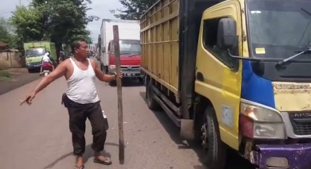 Seorang pria terlihat sedang menghampiri salah satu truk batu bara yang sedang mengantri macet. Foto: Ist